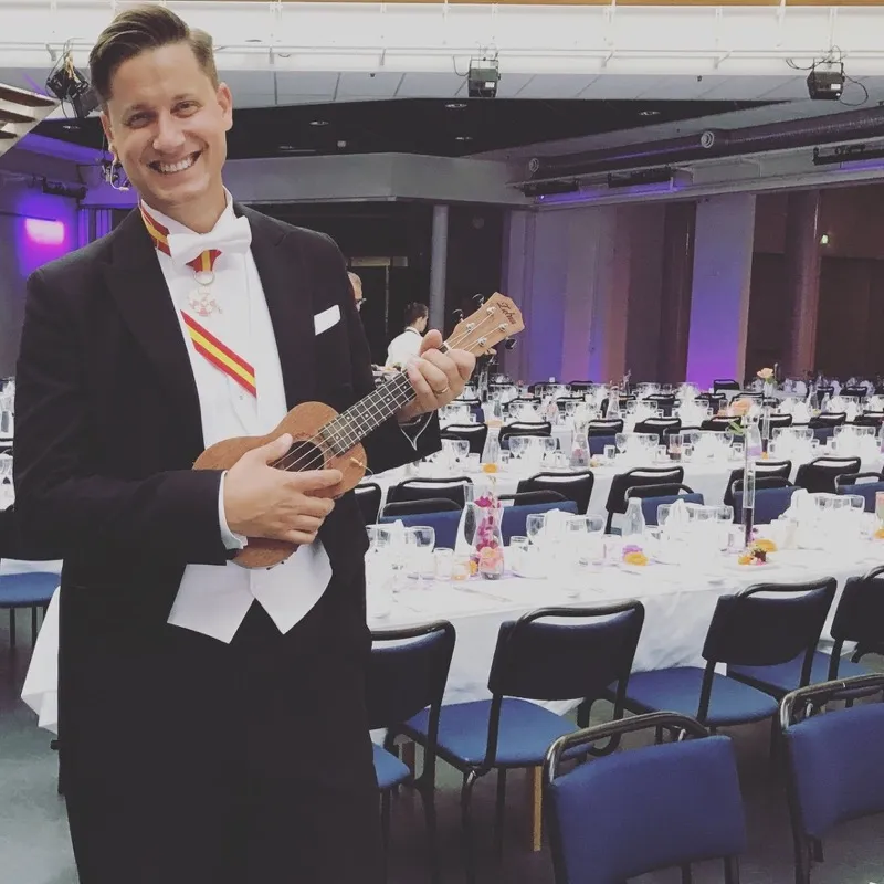 Alexander Åkerberg som konferencier vid Linköpings universitets promoveringsmiddag, i frack med orden och ukulele